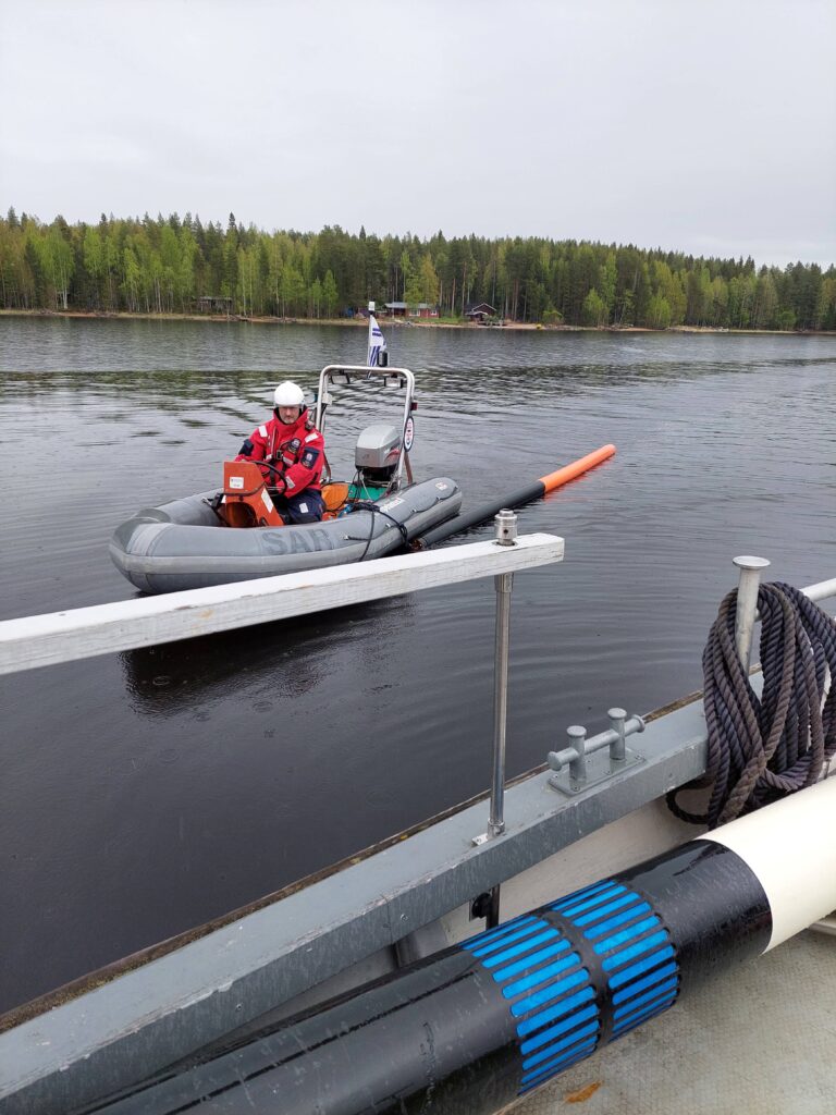 Kumivene hinaa merimerkkiä isomman aluksen luokse.