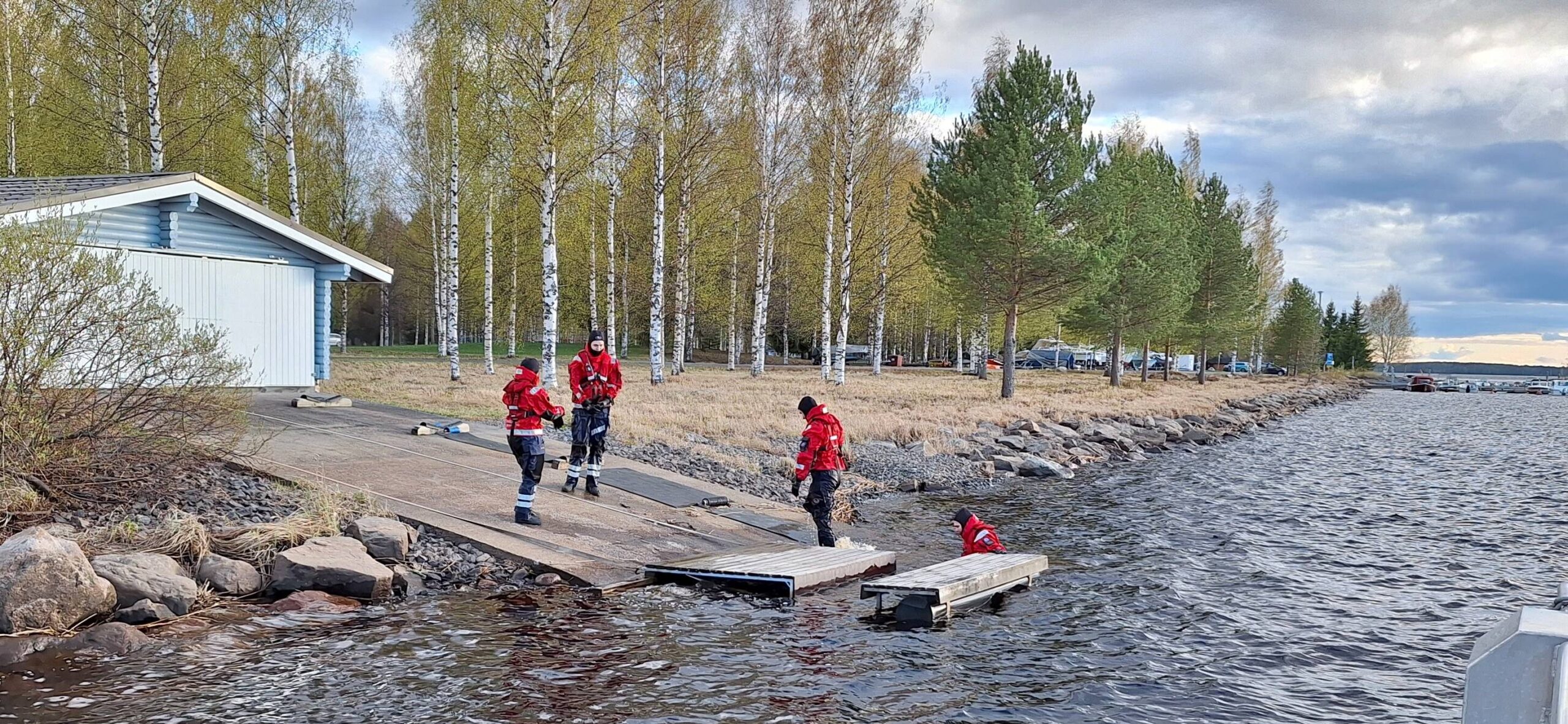 Pelastuspukuihin pukeutuneet ihmiset veden äärellä.